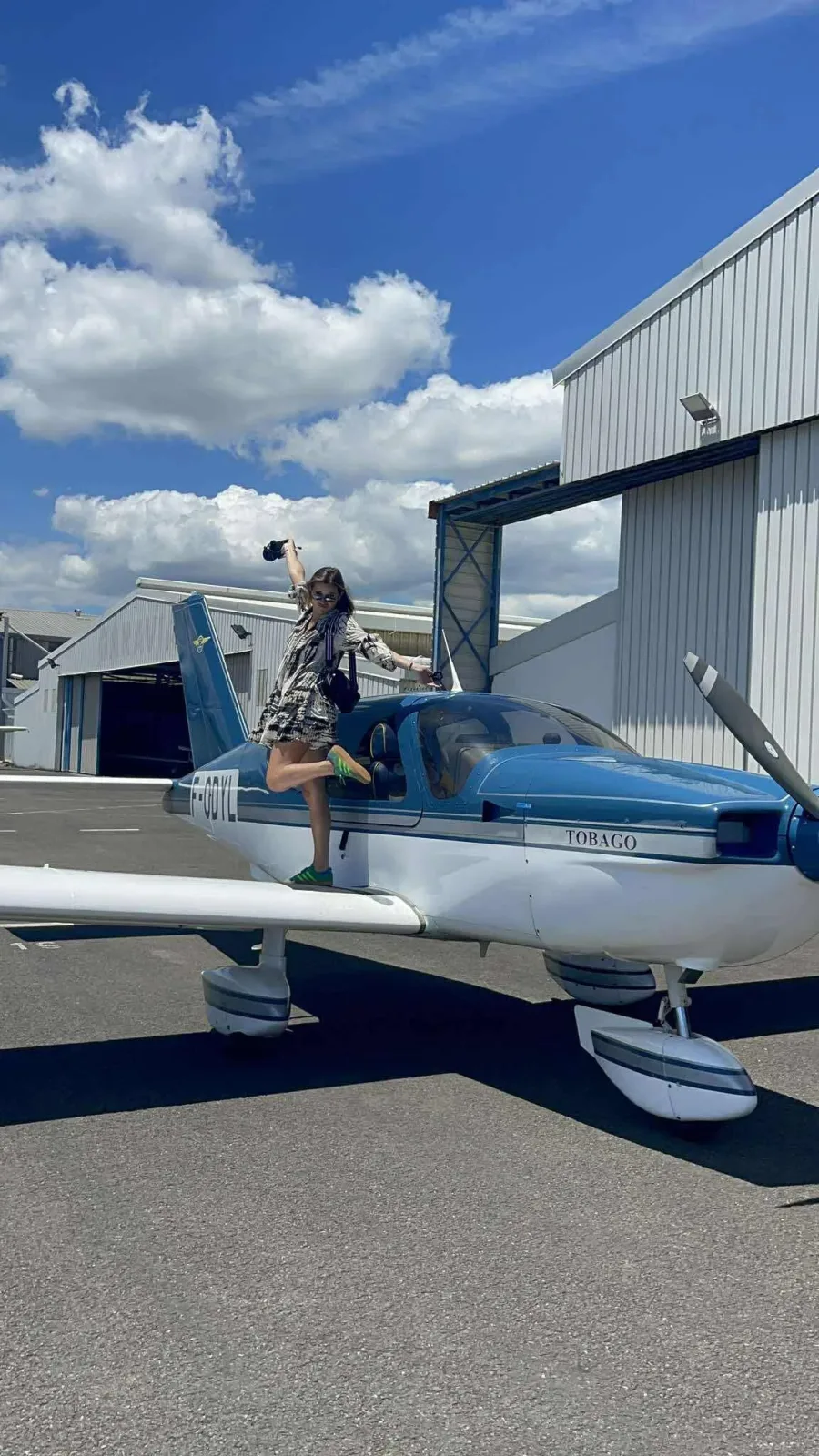 SOCATA TB10 Tobago F-ODYL au sol devant le hangar, une passagère posant sur l'aile